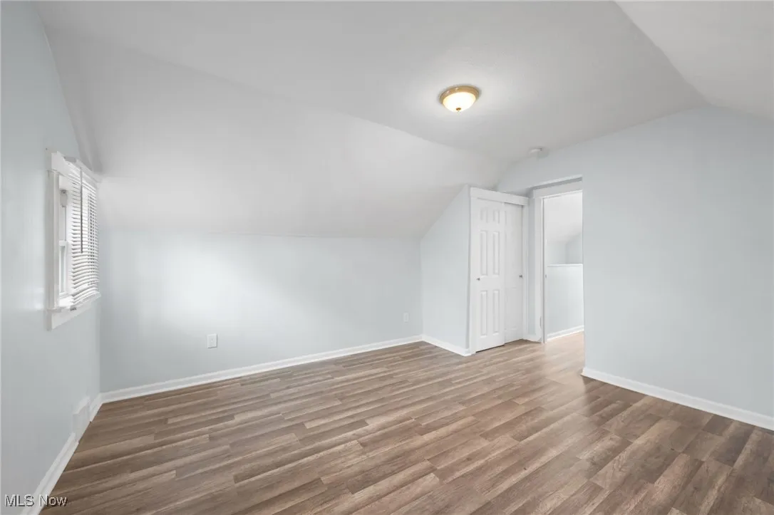 Bedroom with baseboards, vaulted ceiling, and wood style floors