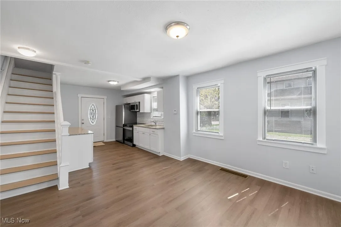 Unfurnished living room featuring wood style floors, and baseboards