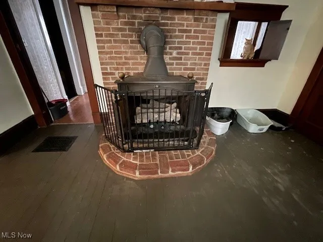 Room details featuring visible vents, wood finished floors, and a wood stove