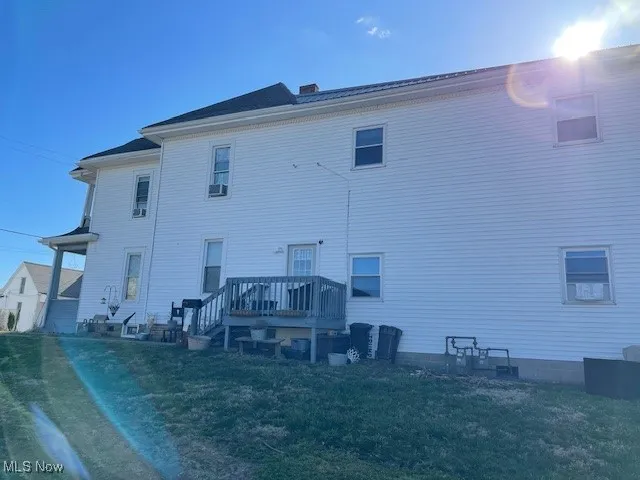 Back of property featuring a wooden deck and a lawn