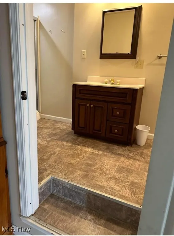Bathroom featuring vanity, stone finish flooring, and baseboards