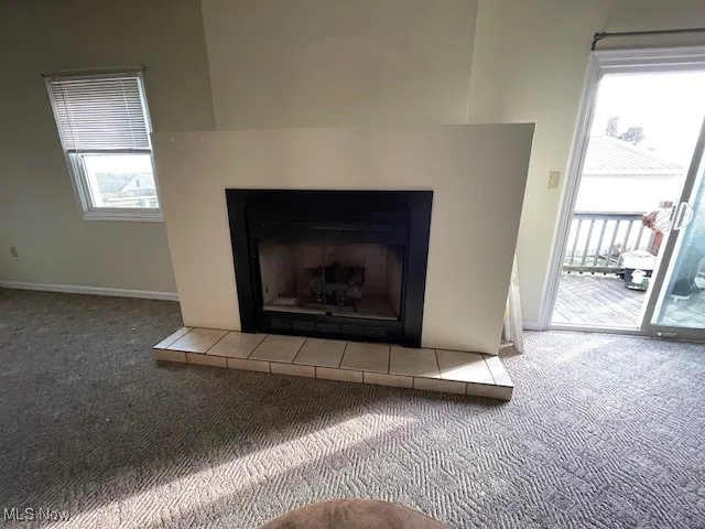 Room details with a tile fireplace, carpet, and baseboards