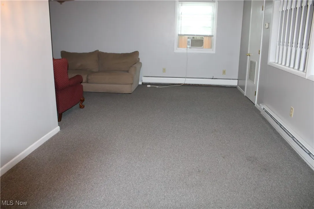 Living area featuring a baseboard radiator, carpet flooring, and cooling unit
