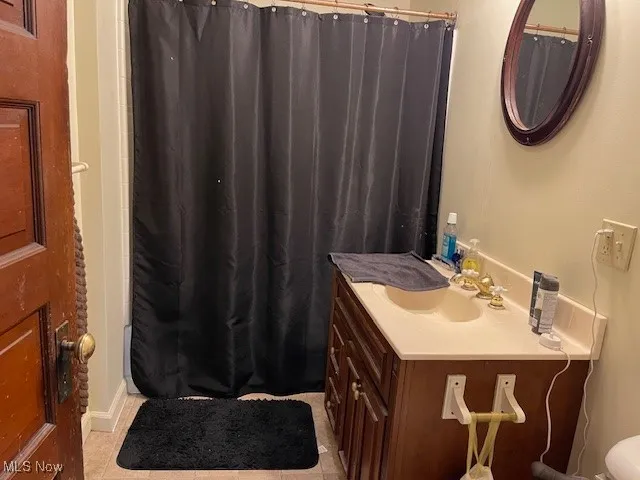 Full bathroom featuring tile patterned floors, curtained shower, and vanity