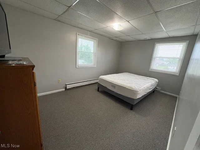 Bedroom featuring a baseboard radiator, a drop ceiling, and carpet floors