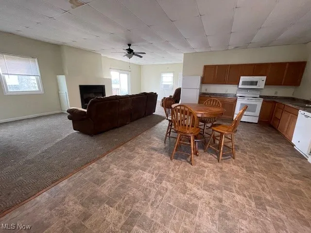 Carpeted dining room with a fireplace, ceiling fan, a sink, and a healthy amount of sunlight