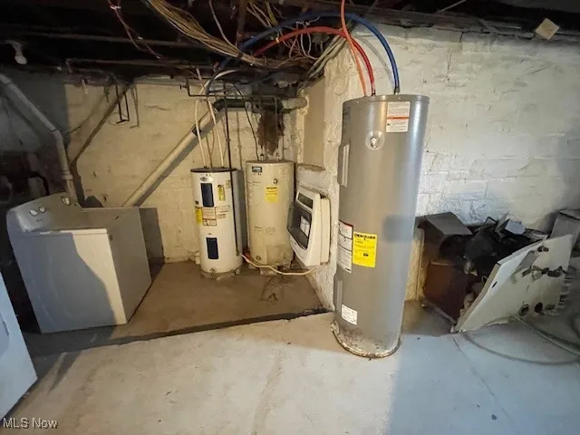 Utility room featuring heating unit, water heater, and washer / dryer