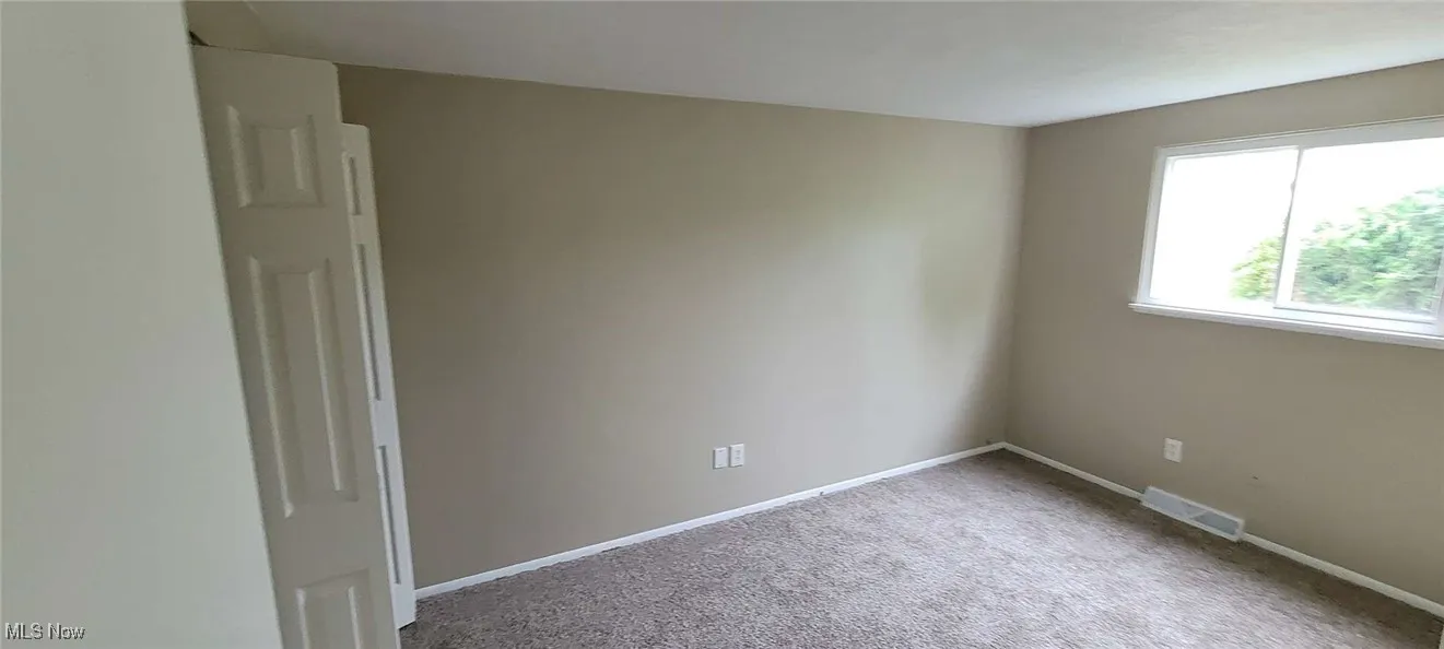 Carpeted spare room featuring baseboards