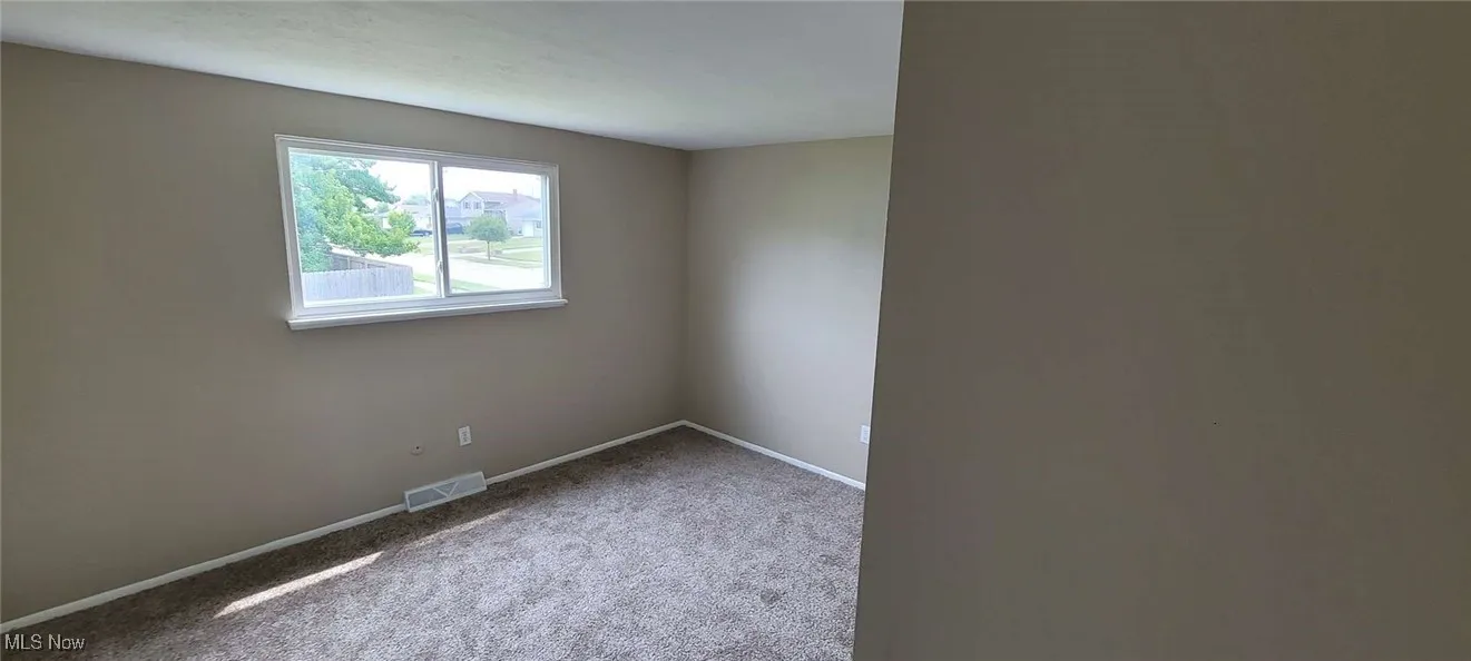 Carpeted spare room with baseboards