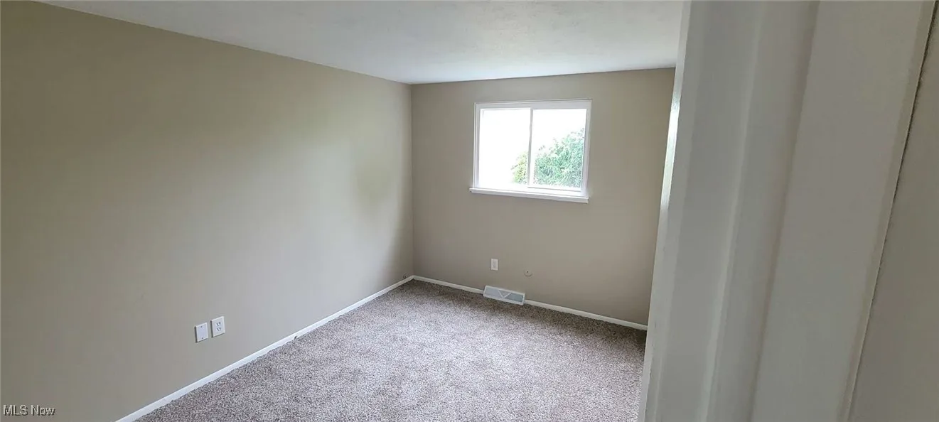 Empty room featuring carpet flooring and baseboards