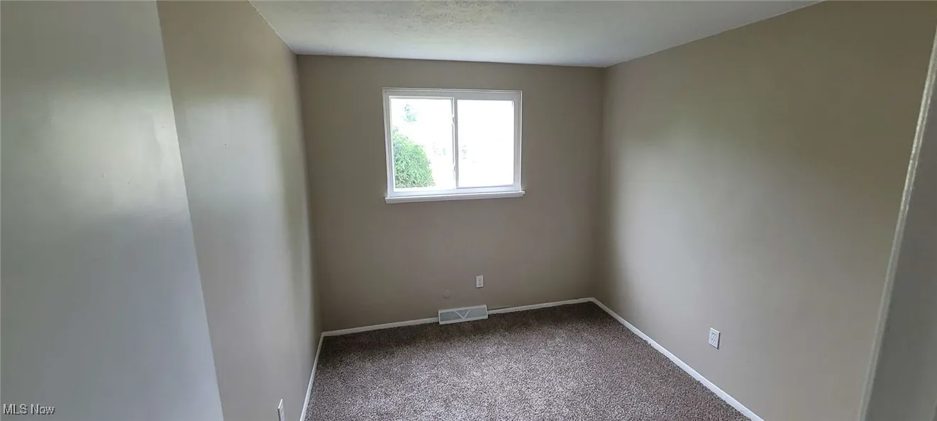 Empty room featuring carpet flooring and a textured ceiling