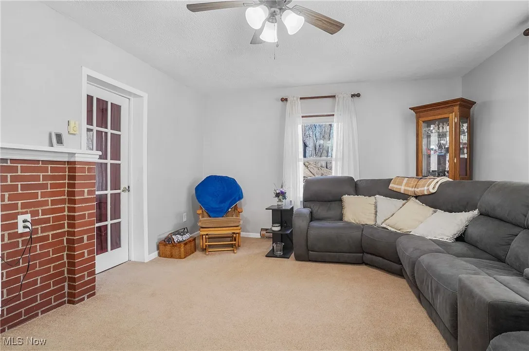 Living room featuring baseboards, a textured ceiling, ceiling fan, and carpet