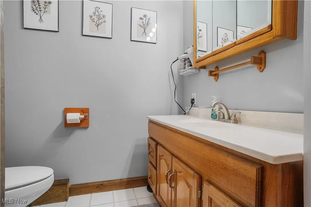 Half bathroom featuring baseboards, toilet, vanity, and tile patterned floors