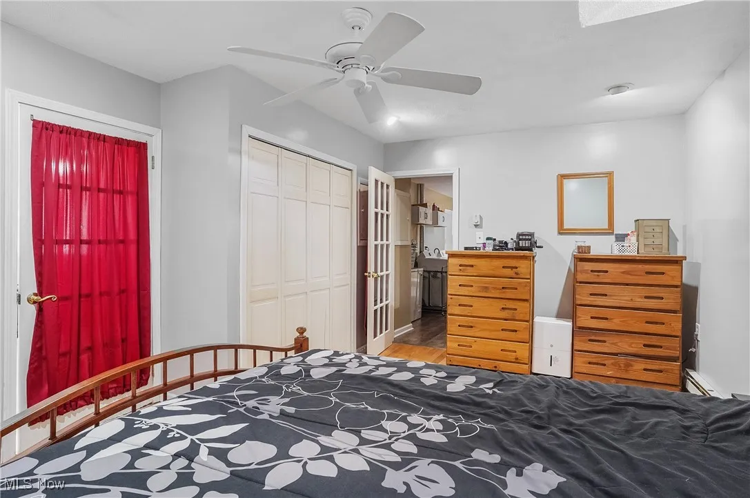 Bedroom featuring a closet, wood finished floors, a ceiling fan, and a baseboard radiator