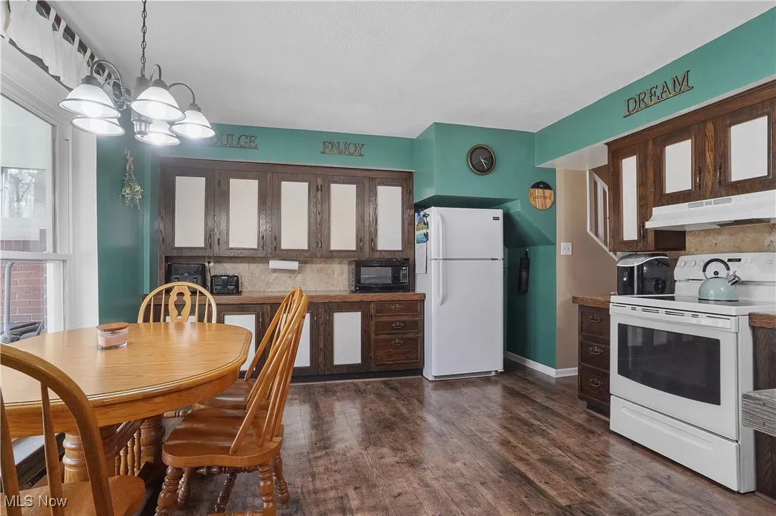 Dining room featuring dark wood-style floors, baseboards, and a chandelier