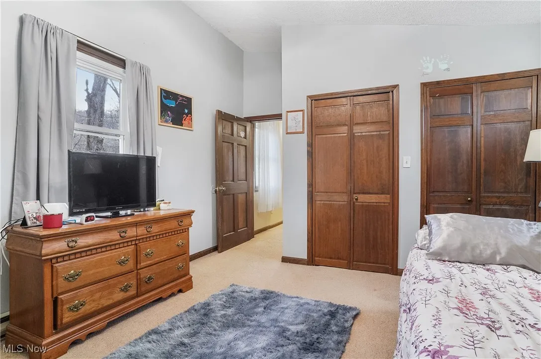 Bedroom featuring two closets, light carpet, and baseboards