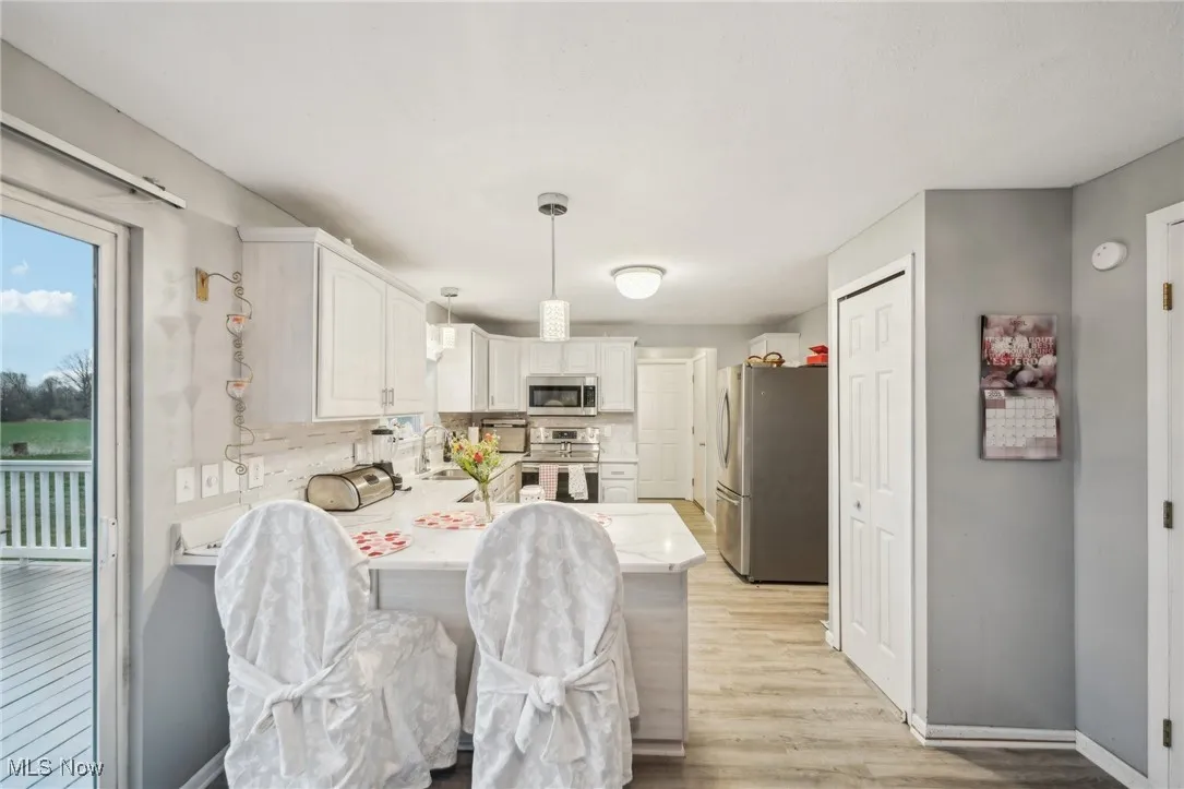 Kitchen with light countertops, a peninsula, light wood finished floors, appliances with stainless steel finishes, and a sink