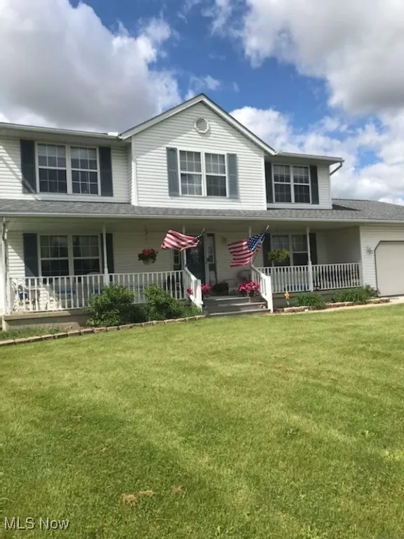 View of front of property featuring covered porch, a garage, and a front yard