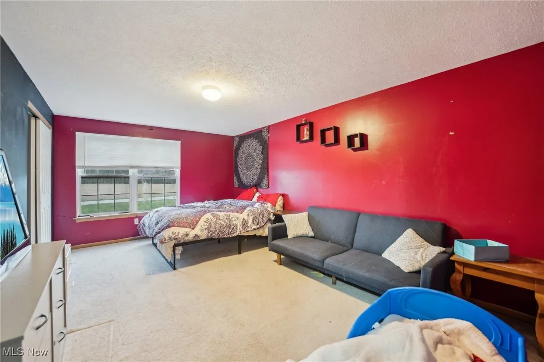 Carpeted bedroom featuring an accent wall and a textured ceiling