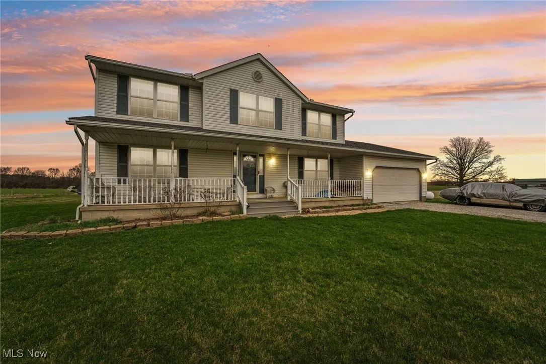 View of front of property featuring a front yard, a porch, driveway, and a garage