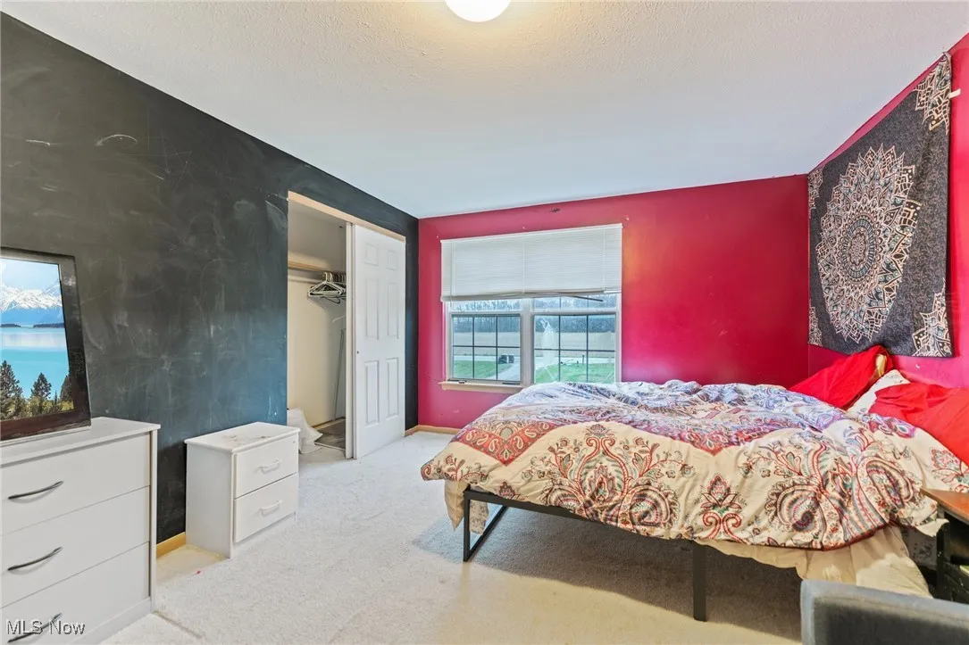 Bedroom with carpet flooring, baseboards, an accent wall, a textured ceiling, and a closet