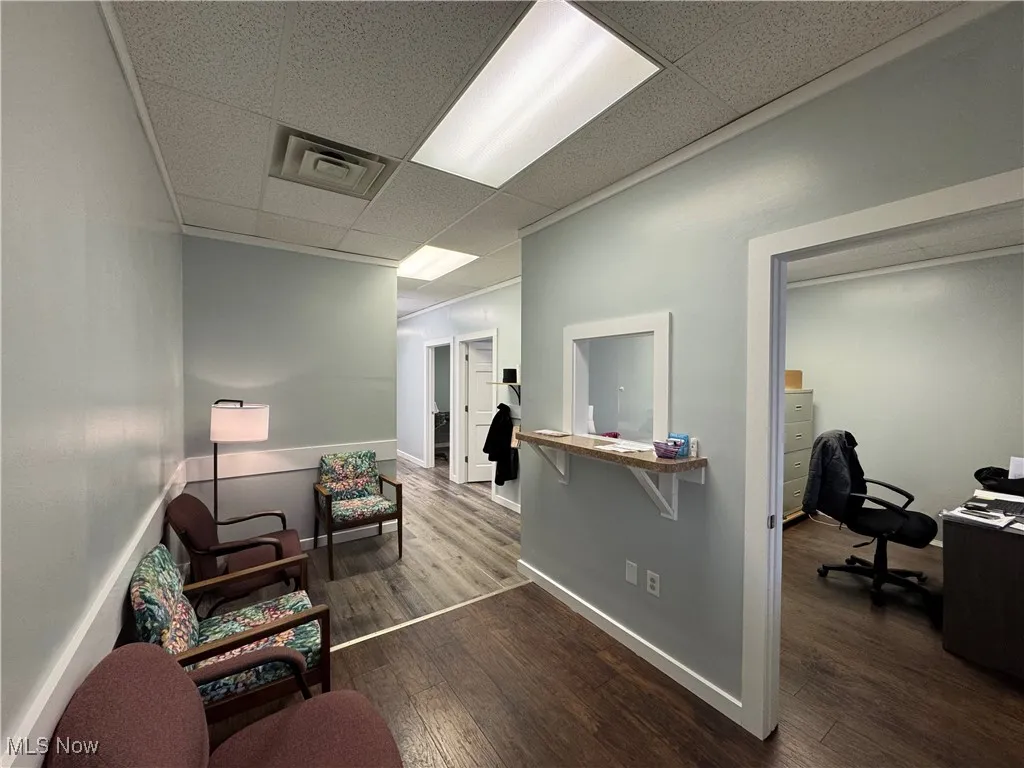 Reception area with a drop ceiling, visible vents, baseboards, and wood finished floors