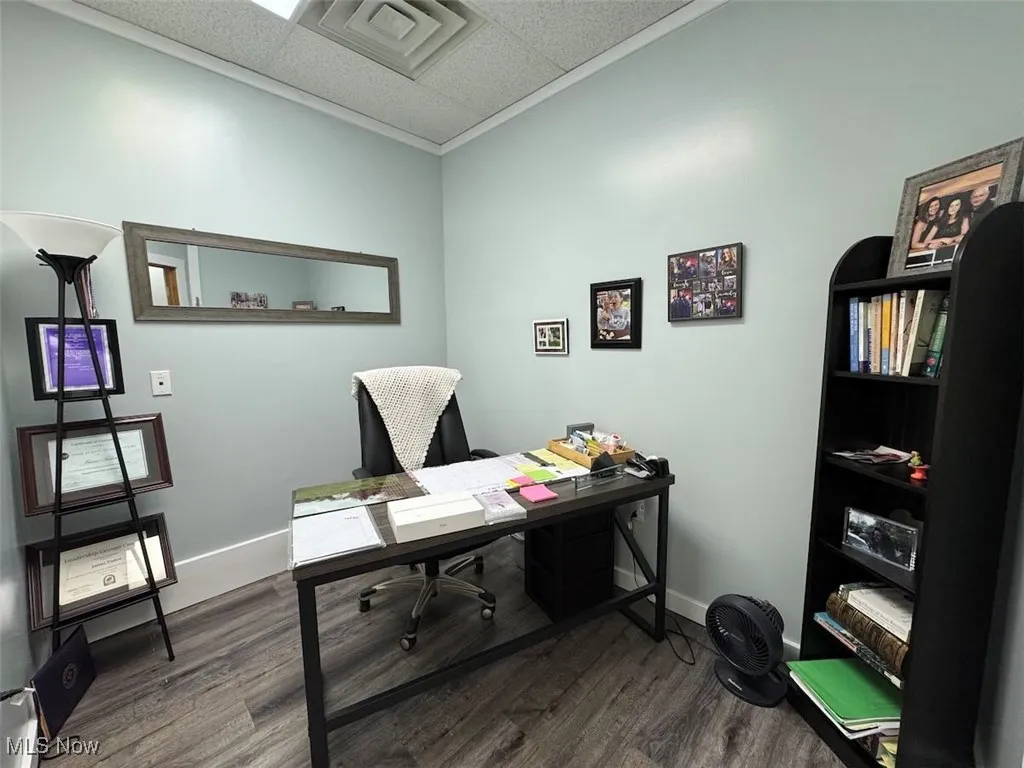 Office with a drop ceiling, dark wood-type flooring, and baseboards