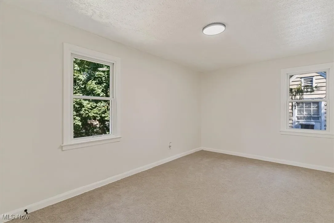 Unfurnished room featuring light carpet and a textured ceiling