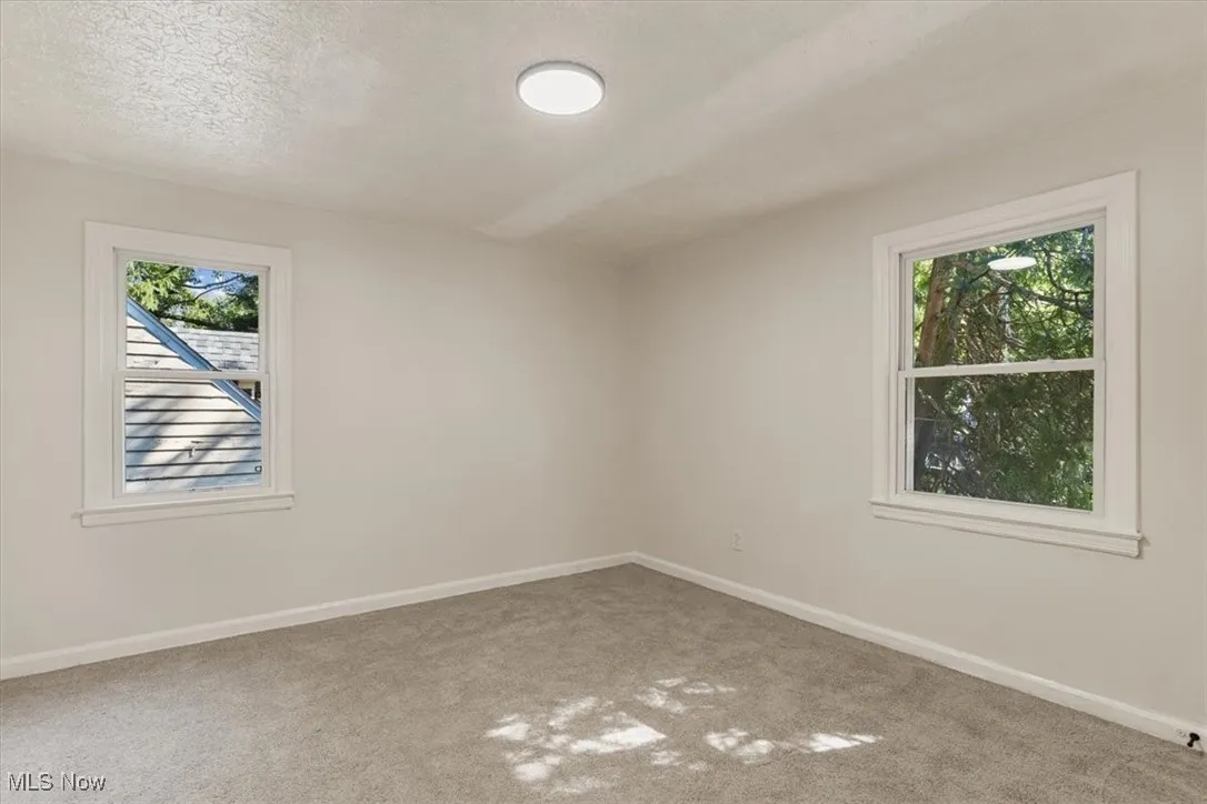 Carpeted empty room featuring baseboards and a textured ceiling