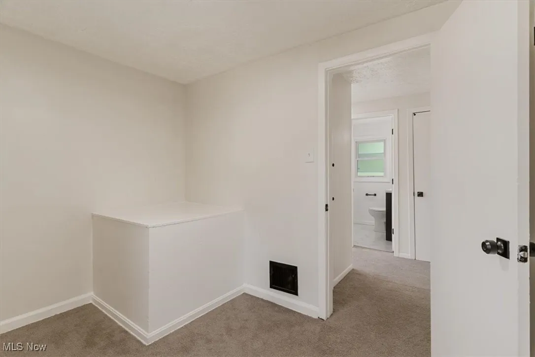 Hallway featuring carpet flooring and a textured ceiling