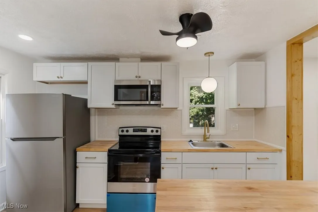 Kitchen featuring appliances with stainless steel finishes, white cabinetry, and a textured ceiling