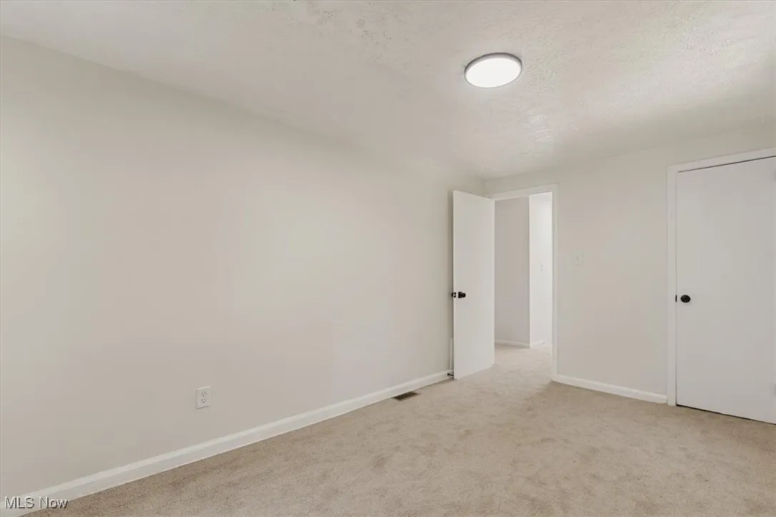 Unfurnished bedroom with a textured ceiling and light carpet