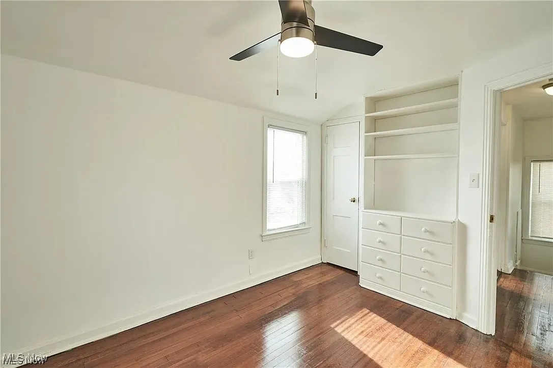 Unfurnished bedroom featuring a ceiling fan, baseboards, vaulted ceiling, and dark wood finished floors