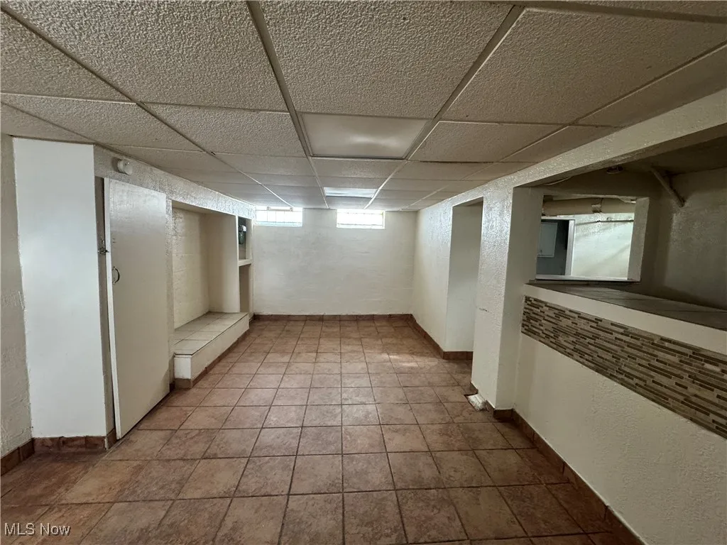 Below grade area with baseboards, tile patterned floors, and a paneled ceiling
