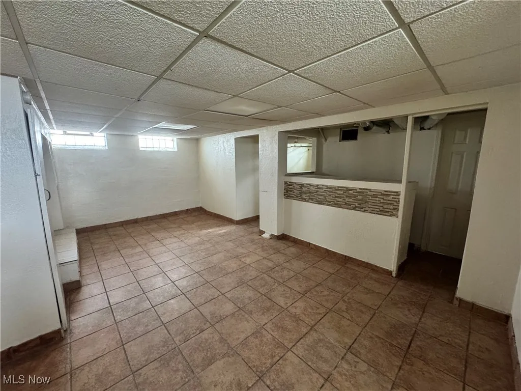 Basement featuring baseboards and a drop ceiling