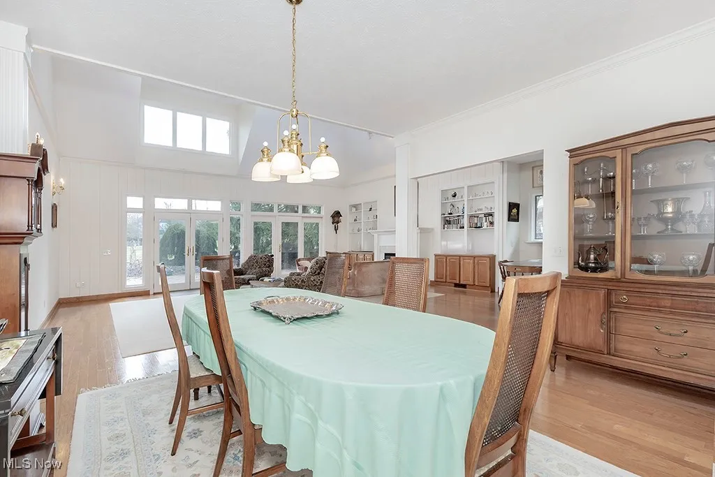 Dining space featuring a notable chandelier, crown molding, light wood-style flooring, and french doors