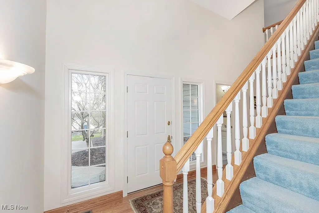 Foyer featuring stairs, a high ceiling, and wood finished floors