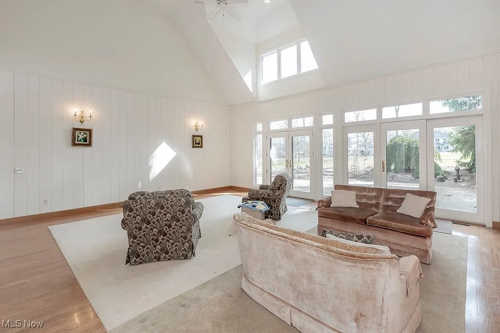 Living room with high vaulted ceiling, ceiling fan, and light wood-type flooring