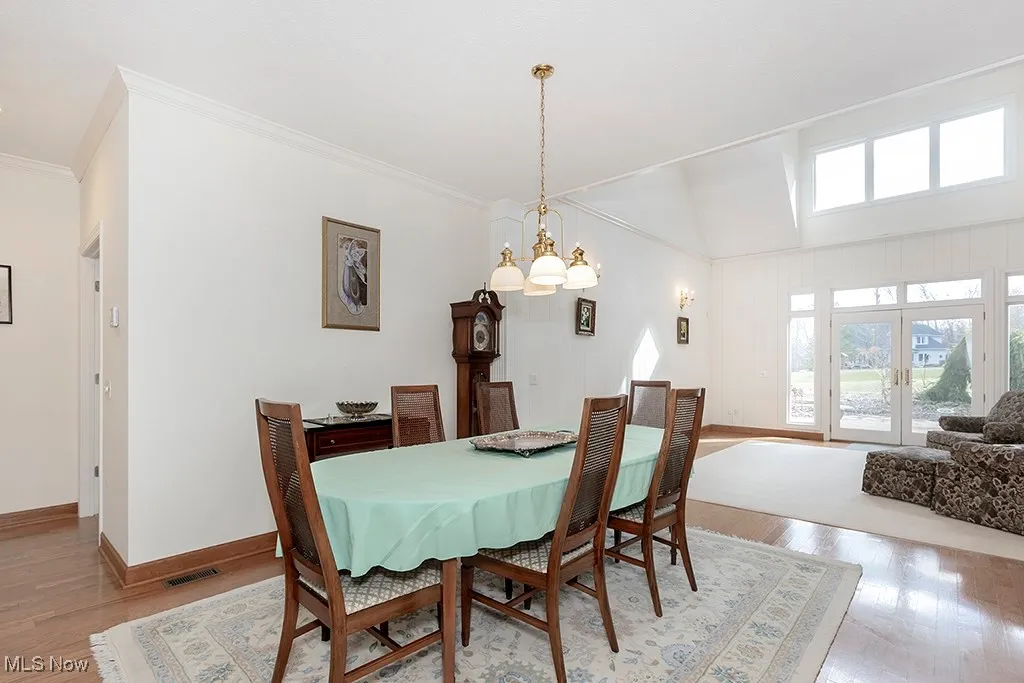 Dining area with ornamental molding, baseboards, a chandelier, visible vents, and wood finished floors