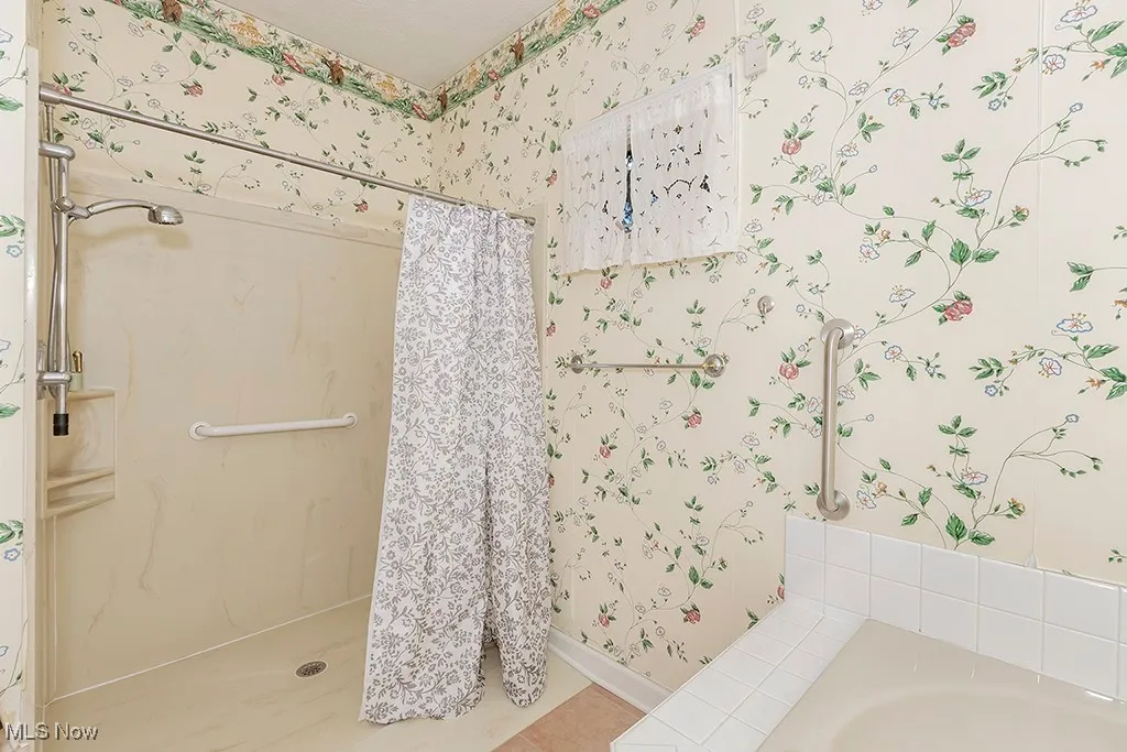 Primary Bathroom with tile patterned flooring, baseboards, wallpapered walls, a stall shower, and a bath