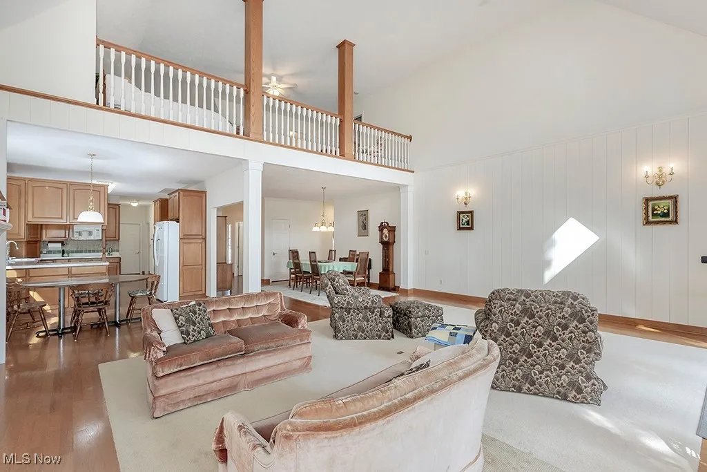 Living room featuring wood finished floors, a towering ceiling, and ornate columns