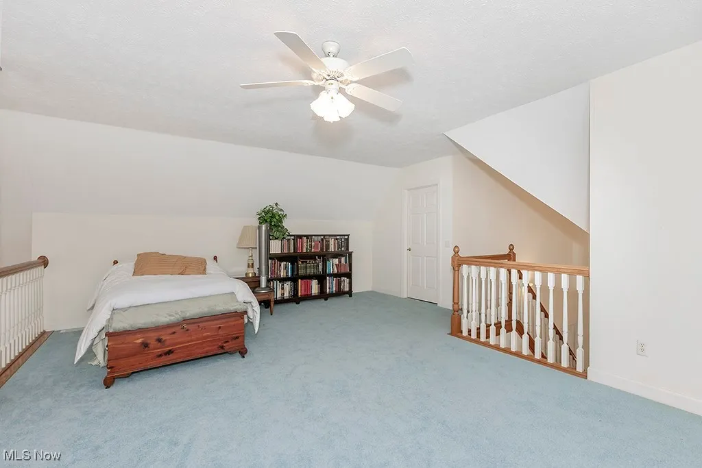  Featuring carpet floors, a textured ceiling, vaulted ceiling, and a ceiling fan