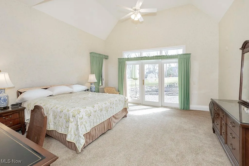 Primary Bedroom with high vaulted ceiling, baseboards, access to outside, a ceiling fan, and light colored carpet