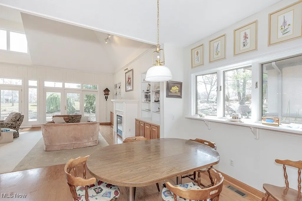 Dining room featuring light wood-style flooring, a wealth of natural light, a glass covered fireplace, and visible vents