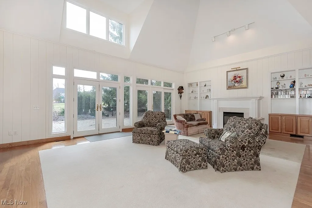 Living area with a wealth of natural light, a fireplace, french doors, and built in shelves