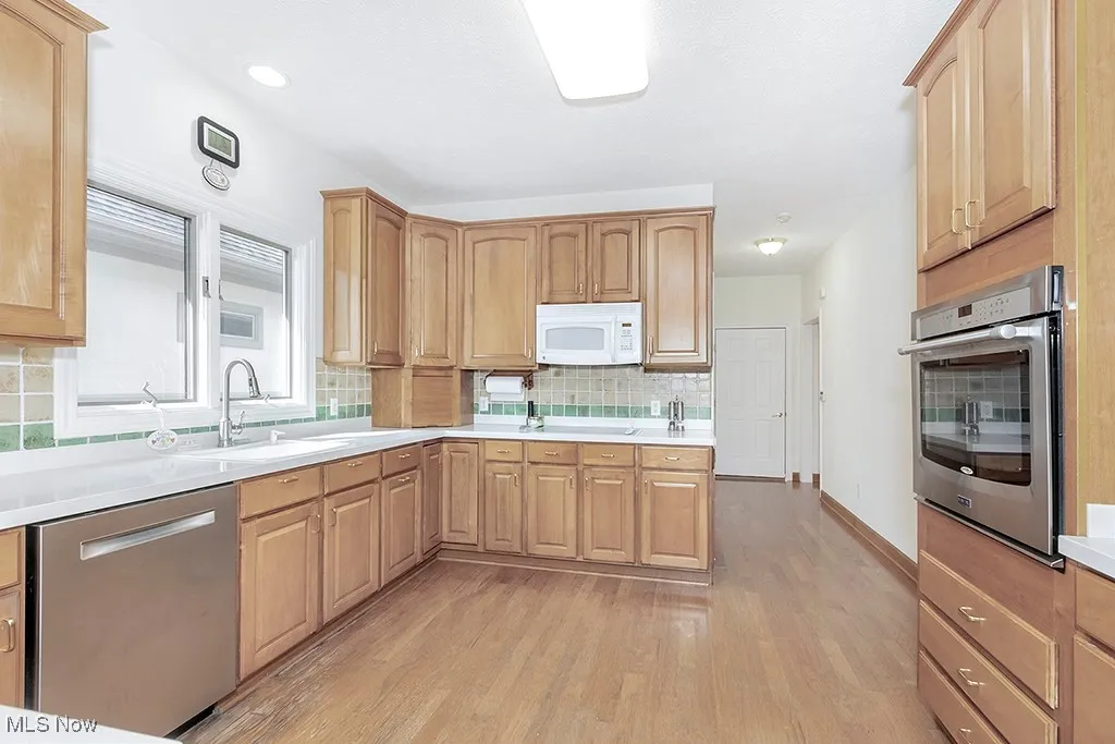 Kitchen featuring light wood finished floors, backsplash, a sink, and stainless steel appliances