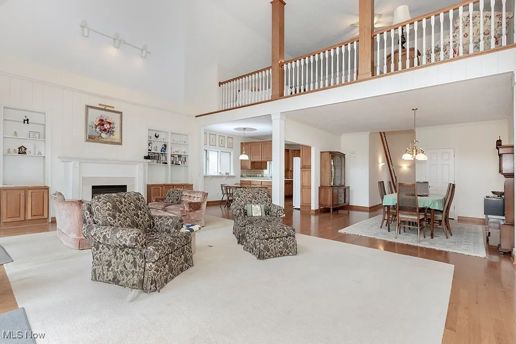 Living room with a chandelier, baseboards, a fireplace, wood finished floors, and a high ceiling