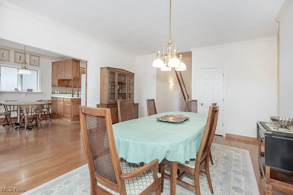 Dining space featuring baseboards, ornamental molding, an inviting chandelier, and light wood-style floors