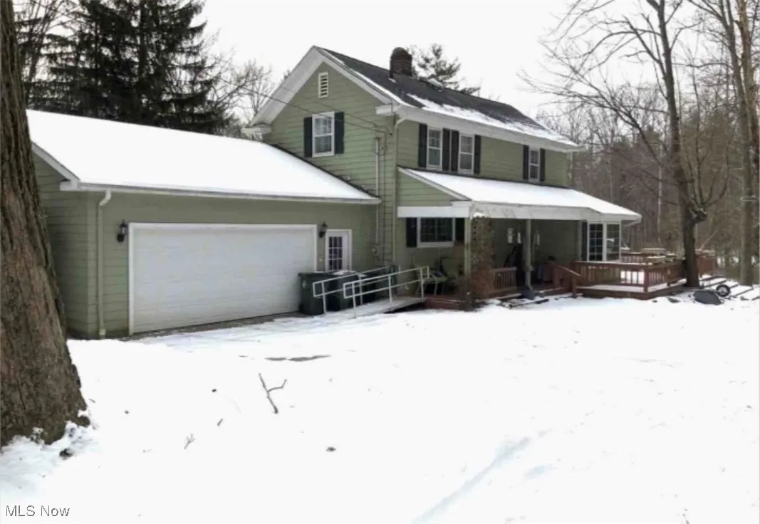 View of front of property featuring a chimney, a deck, and an attached garage