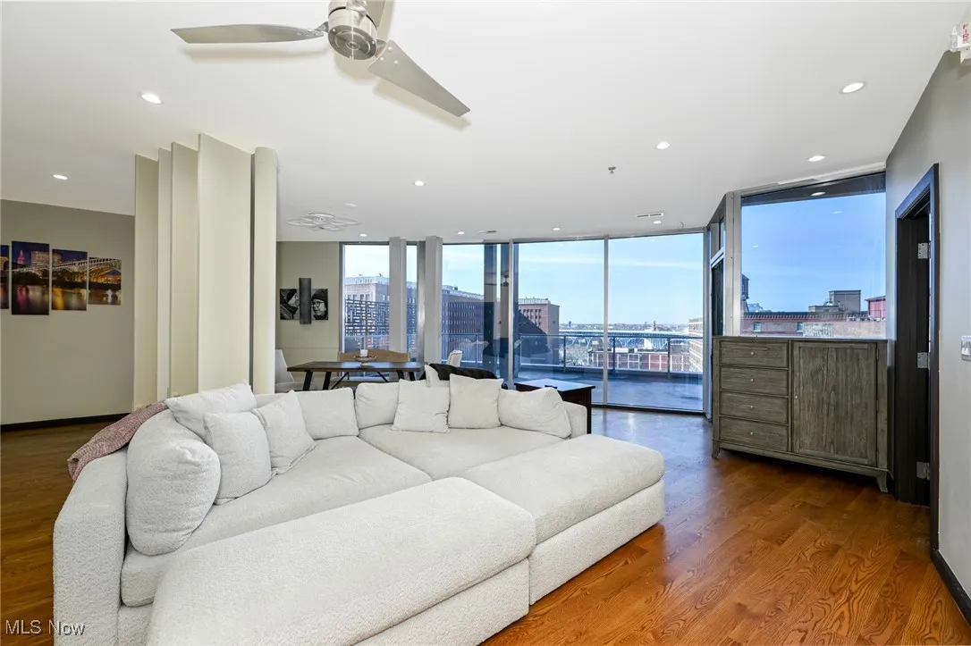 Living room with a city view, wood finished floors, recessed lighting, a ceiling fan, and expansive windows
